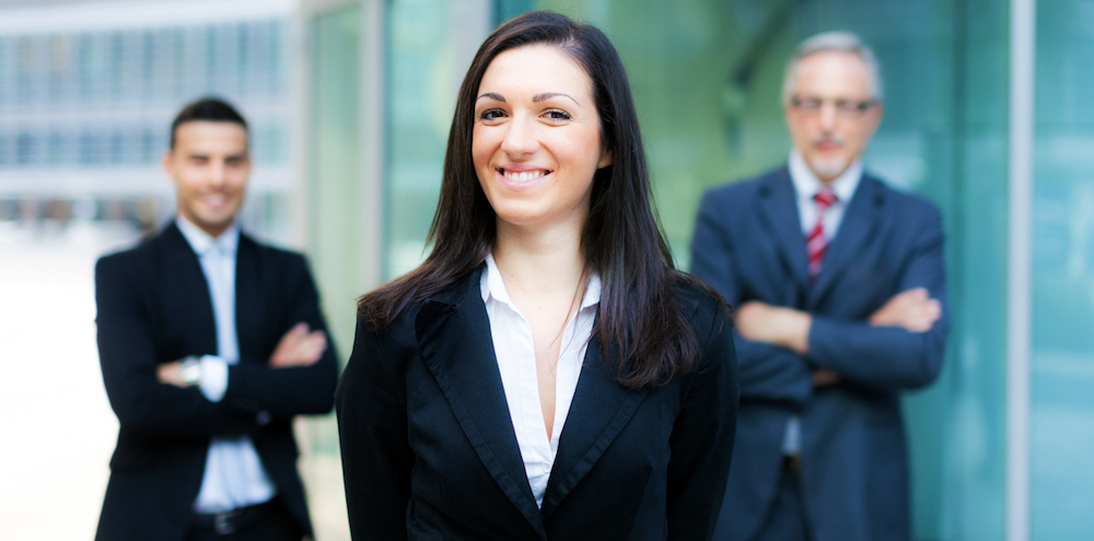 Business woman in foreground with two businessmen behind her